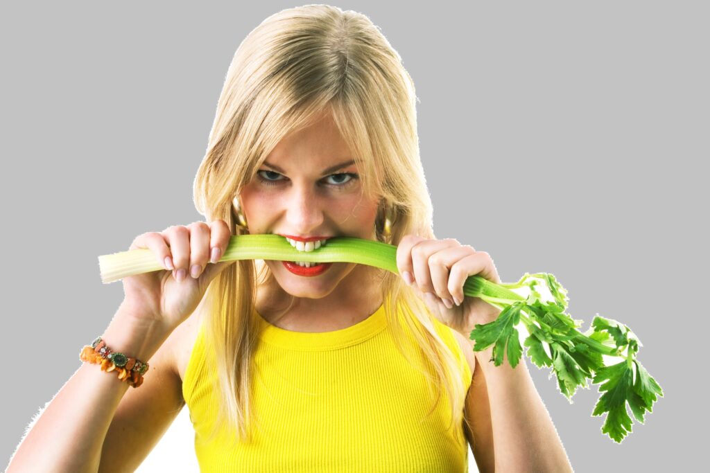 Ung kvinde MED STÆRKE TÆNDER tygger på selleri